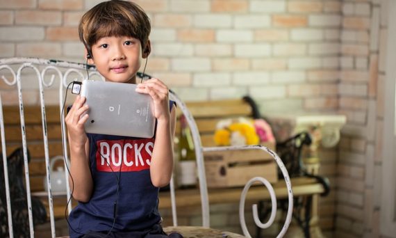 Barn som lyssnar i hörlurar kopplade till en surfplatta.